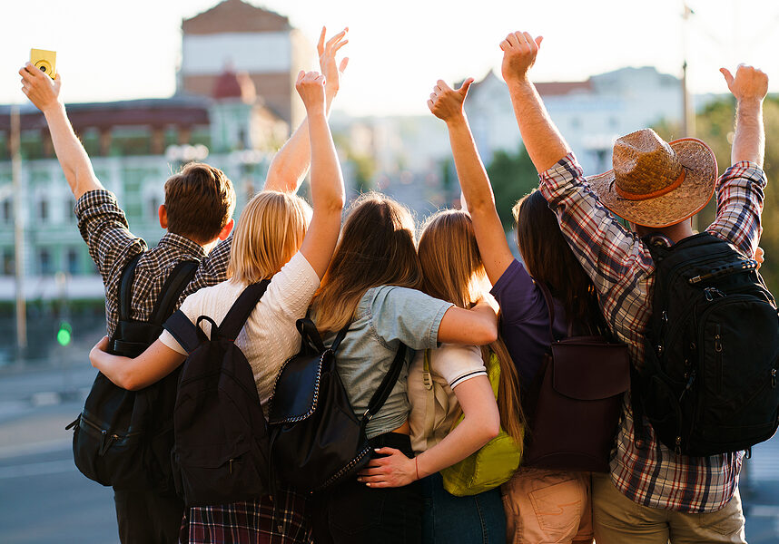 Traveling, sightseeing, group travel, city tour, student exchange program, vacation, holiday, togetherness and friendship. People with backpacks rising hands, joy and positivity